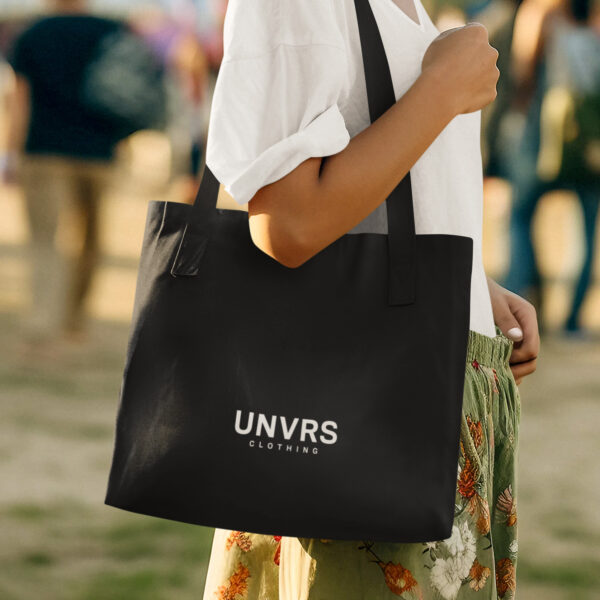 UNVRS branded tote bag with a minimalist design and durable fabric, ideal for carrying daily essentials or adding a stylish touch to any outfit. Featuring sturdy handles and the signature UNVRS logo, this tote is perfect for everything from shopping to beach days, embodying Ibiza’s casual yet chic streetwear vibe.